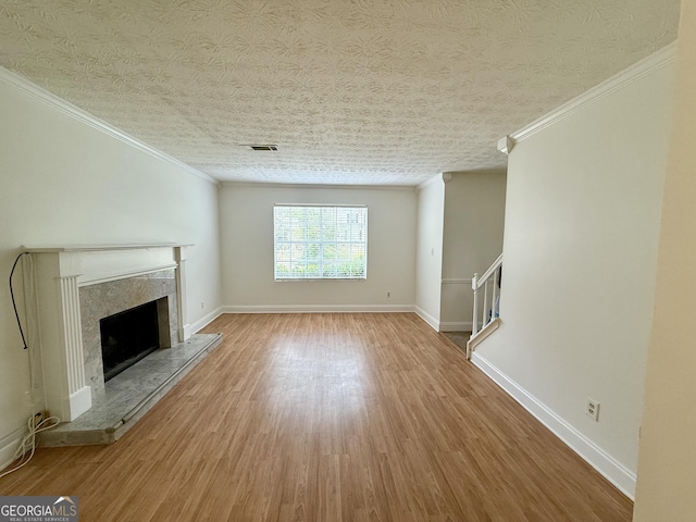 unfurnished living room with a high end fireplace, visible vents, crown molding, and wood finished floors