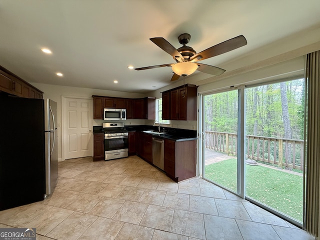 kitchen featuring recessed lighting, a ceiling fan, dark countertops, stainless steel appliances, and a sink