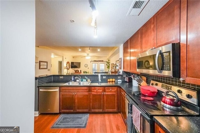 kitchen featuring a peninsula, visible vents, a sink, stainless steel appliances, and decorative backsplash