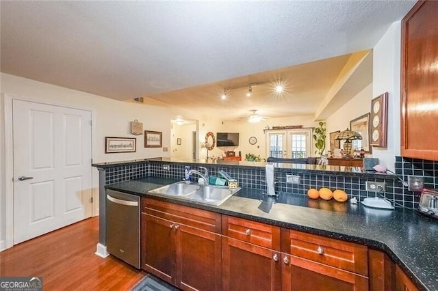 kitchen with dishwasher, a sink, backsplash, and wood finished floors