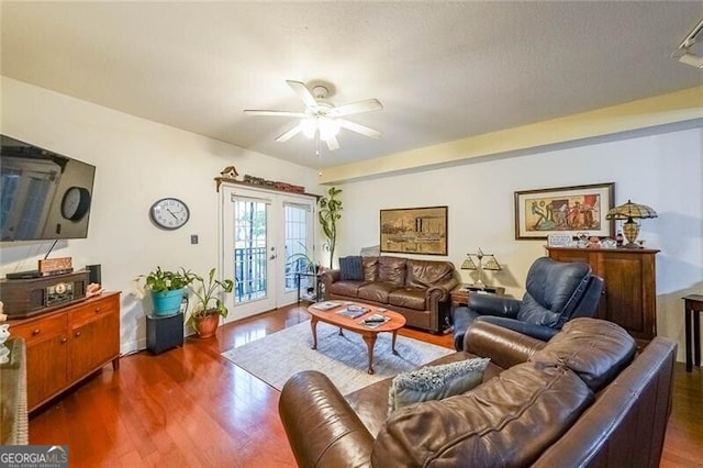 living area with french doors, ceiling fan, and dark wood finished floors