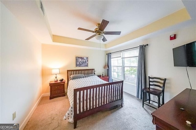 bedroom featuring ceiling fan, carpet, a tray ceiling, visible vents, and baseboards