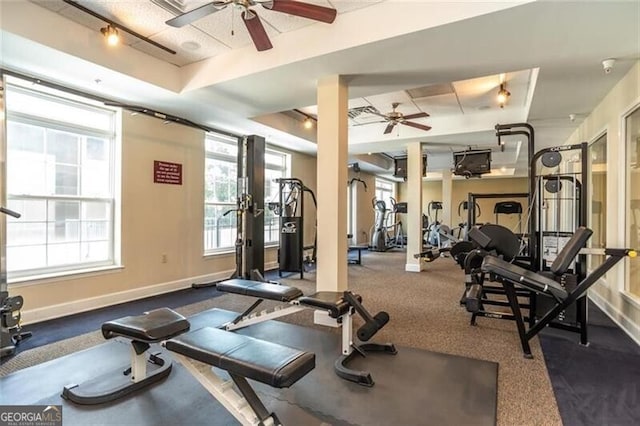 exercise room with baseboards, a ceiling fan, and a raised ceiling