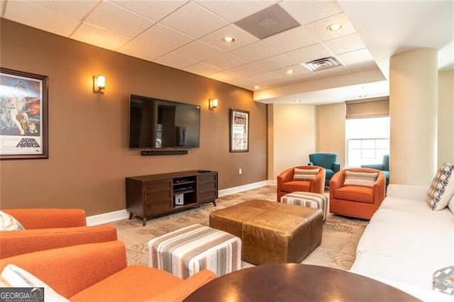 living area featuring visible vents, baseboards, and a paneled ceiling