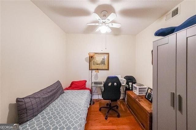 bedroom with wood finished floors, a ceiling fan, and visible vents