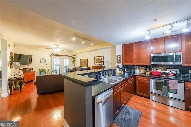 kitchen featuring stainless steel appliances, decorative backsplash, wood finished floors, and dark countertops
