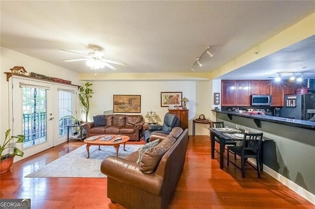 living room featuring track lighting, a ceiling fan, and wood finished floors
