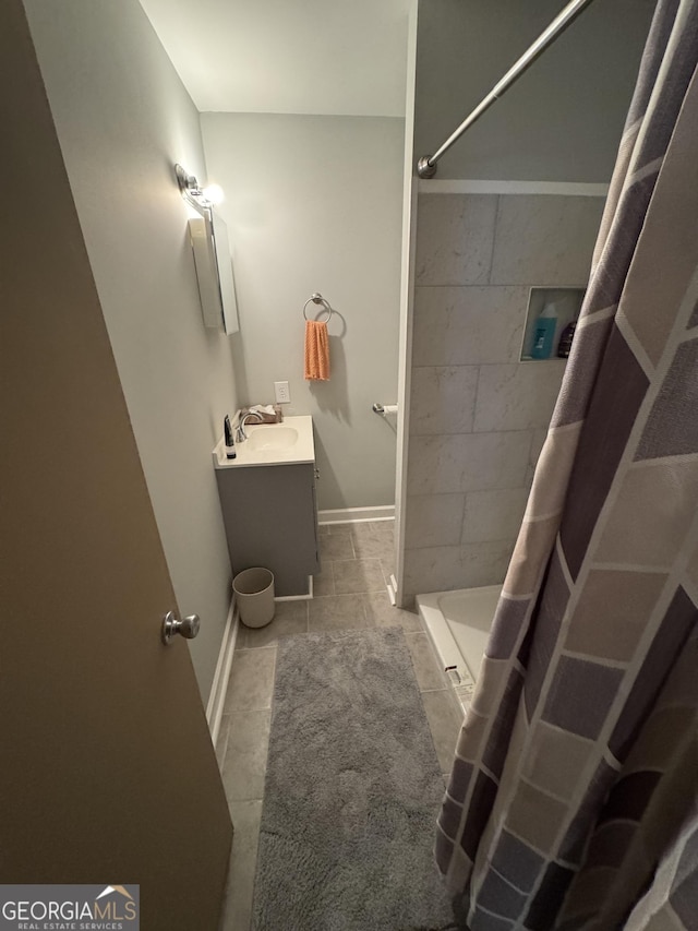 bathroom featuring vanity, baseboards, and a tile shower