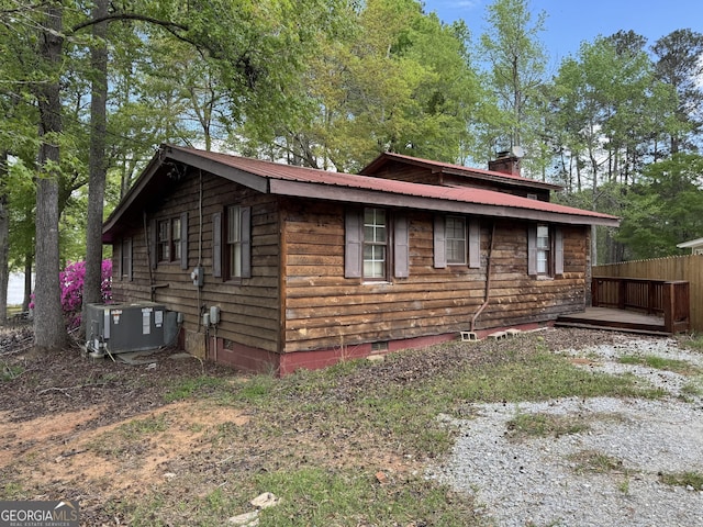 view of side of home with a deck, metal roof, crawl space, a chimney, and central air condition unit