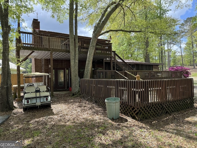 rear view of property featuring a chimney, a wooden deck, and stairs