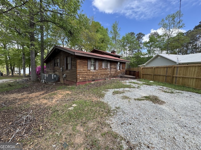 exterior space with central AC, fence, and a chimney