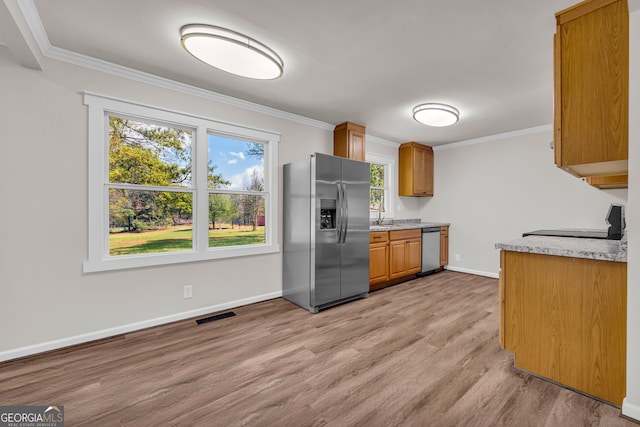 kitchen with crown molding, light wood-style flooring, visible vents, light countertops, and stainless steel appliances