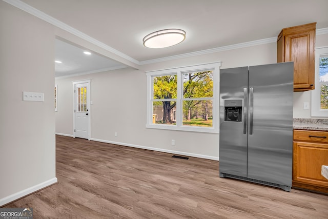 kitchen with ornamental molding, visible vents, stainless steel refrigerator with ice dispenser, light wood finished floors, and baseboards
