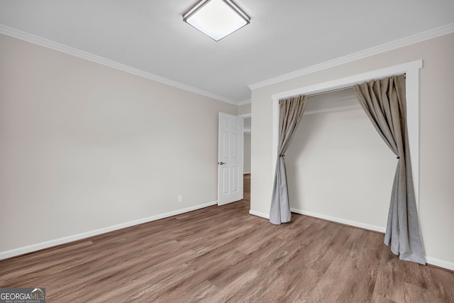 unfurnished bedroom featuring wood finished floors, a closet, baseboards, and ornamental molding