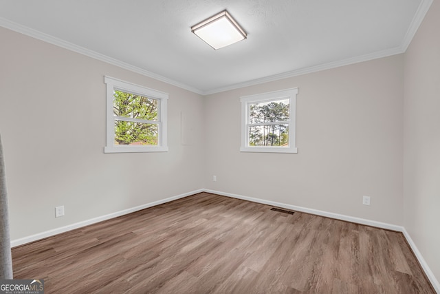unfurnished room with a wealth of natural light, visible vents, baseboards, and wood finished floors