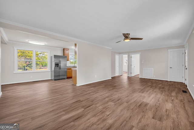 unfurnished living room with visible vents, wood finished floors, ornamental molding, and ceiling fan
