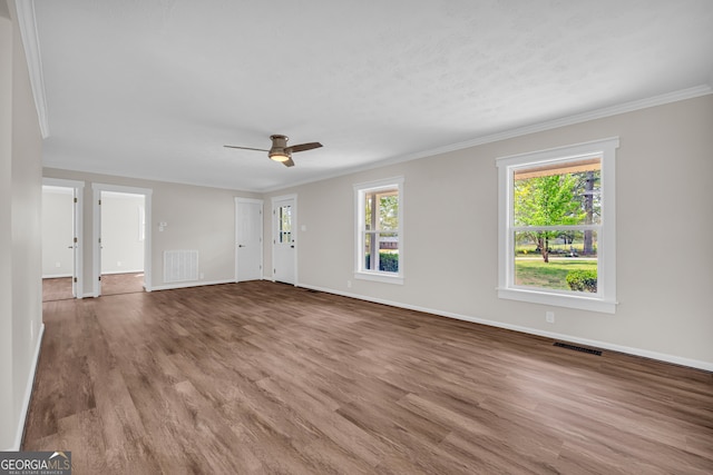 unfurnished living room featuring ornamental molding, visible vents, and plenty of natural light