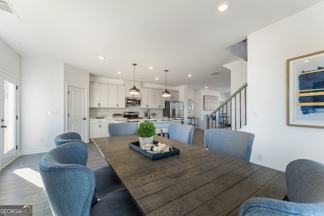 dining room featuring visible vents, baseboards, recessed lighting, wood finished floors, and stairs