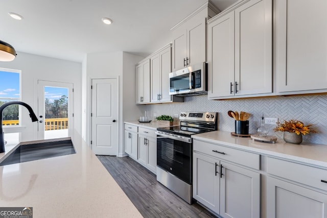 kitchen featuring light countertops, appliances with stainless steel finishes, a sink, and backsplash