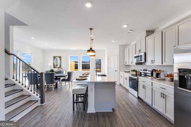 kitchen featuring dark wood-type flooring, backsplash, a healthy amount of sunlight, and stainless steel appliances