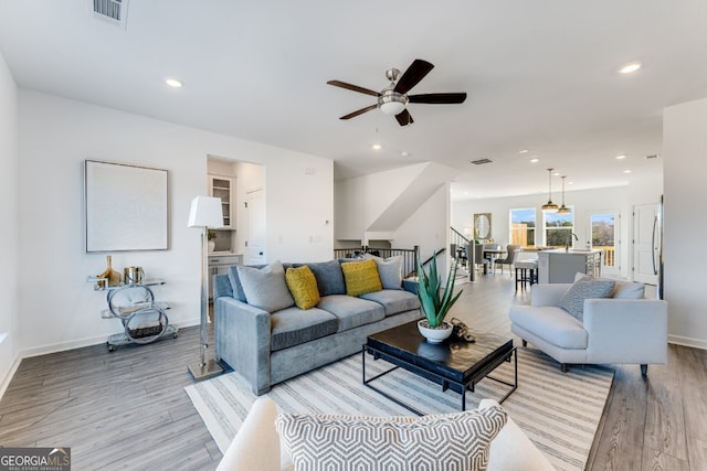 living area with light wood-style floors, ceiling fan, visible vents, and recessed lighting