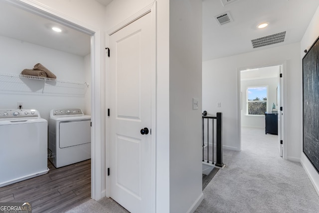 hall featuring visible vents, an upstairs landing, washer and dryer, and carpet floors