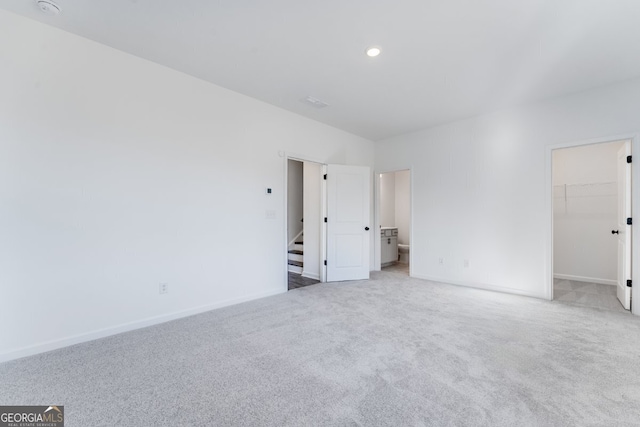 unfurnished bedroom featuring a spacious closet, carpet, baseboards, and connected bathroom