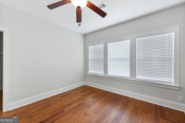 empty room with baseboards, a ceiling fan, visible vents, and hardwood / wood-style flooring