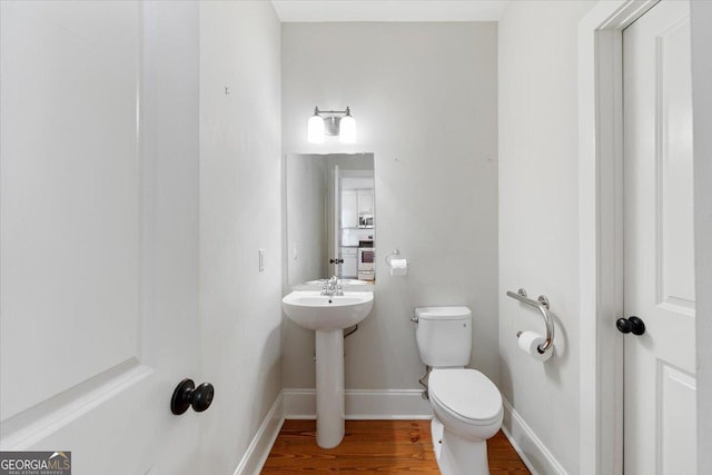 bathroom with toilet, wood finished floors, and baseboards