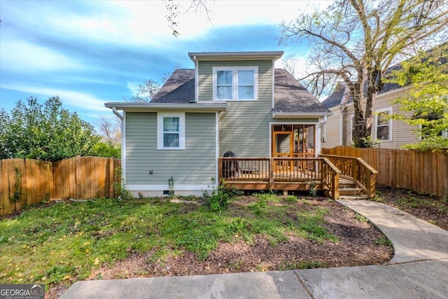 rear view of property featuring a deck, fence private yard, and a shingled roof