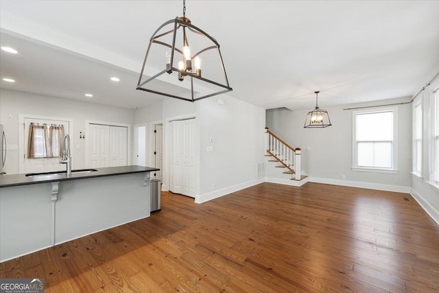 kitchen with a notable chandelier, recessed lighting, dark countertops, dark wood finished floors, and a sink
