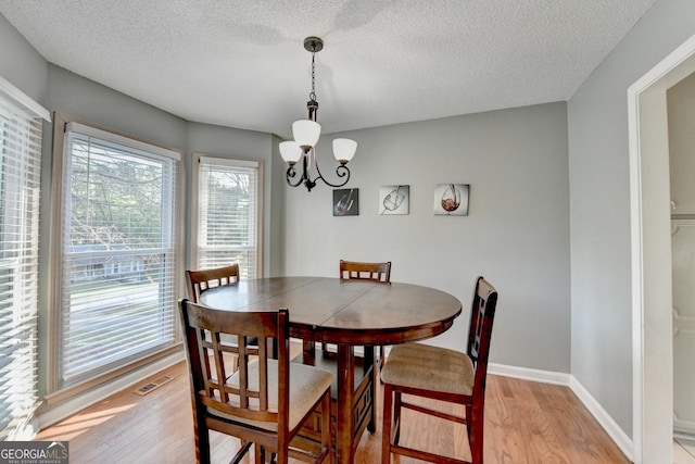 6040 Carriage Dr, Cumming, GA 30028 - dining space with an inviting chandelier, a textured ceiling, visible vents, light wood finished floors, and baseboards