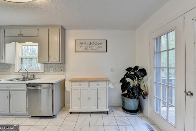 6040 Carriage Dr, Cumming, GA 30028 - kitchen with a textured ceiling, light countertops, decorative backsplash, stainless steel dishwasher, and a sink