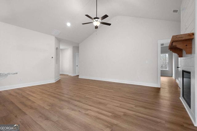 unfurnished living room with baseboards, a fireplace, visible vents, ceiling fan, and high vaulted ceiling