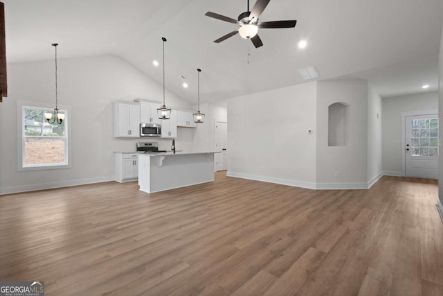 unfurnished living room featuring high vaulted ceiling, light wood finished floors, ceiling fan with notable chandelier, and baseboards