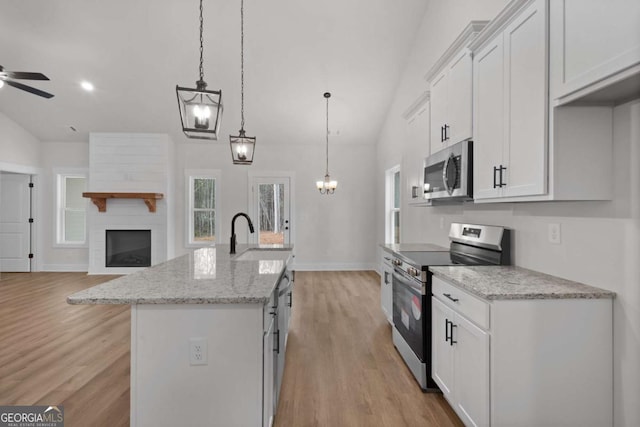 kitchen featuring stainless steel appliances, open floor plan, vaulted ceiling, and a sink