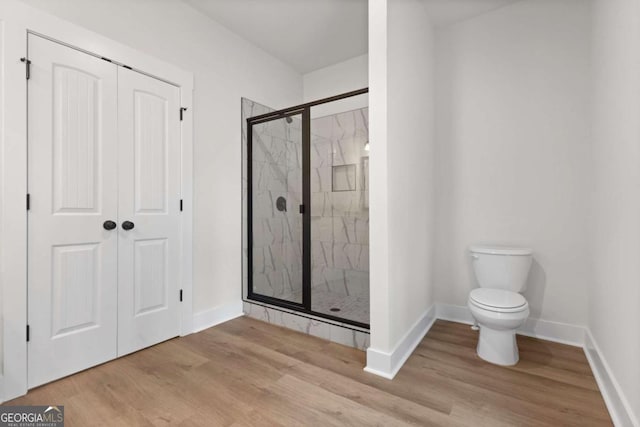 bathroom featuring a shower stall, wood finished floors, and baseboards