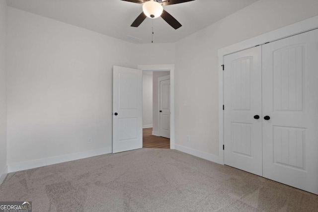 unfurnished bedroom featuring carpet, a closet, baseboards, and a ceiling fan