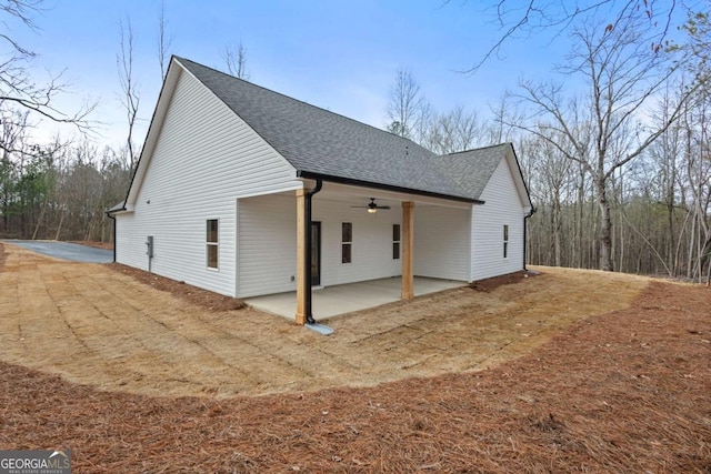 view of side of home featuring a shingled roof, a patio area, and ceiling fan