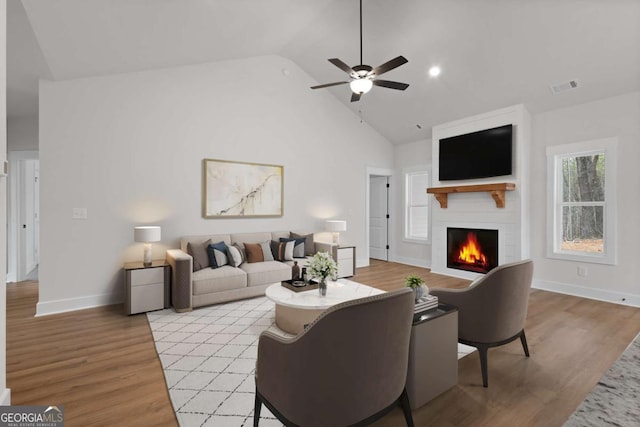 living room featuring visible vents, ceiling fan, light wood-style floors, and a fireplace