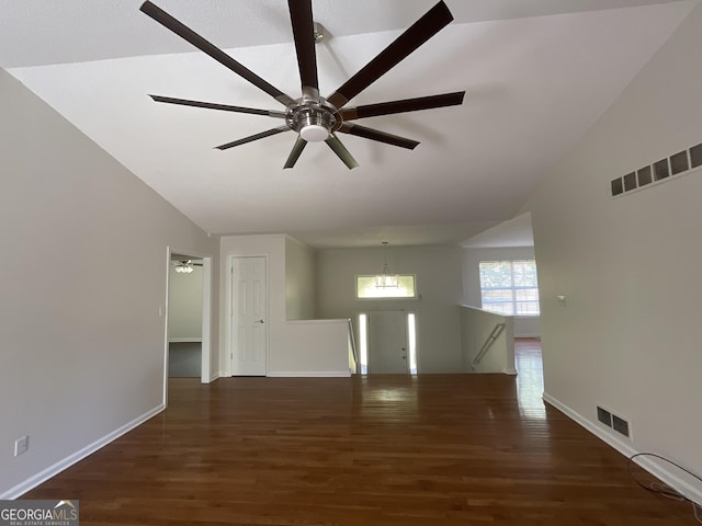 spare room with ceiling fan with notable chandelier, vaulted ceiling, wood finished floors, and visible vents