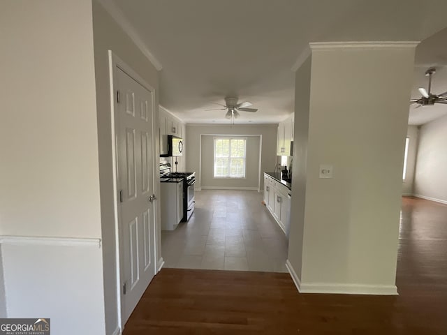 hallway featuring baseboards, ornamental molding, and wood finished floors