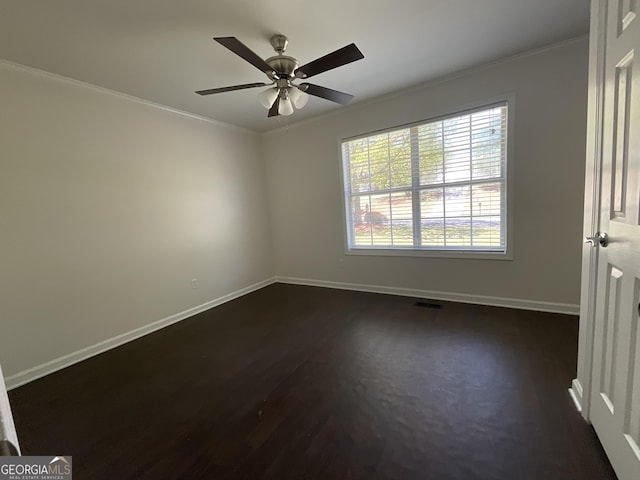 unfurnished room with crown molding, ceiling fan, baseboards, visible vents, and dark wood-style floors