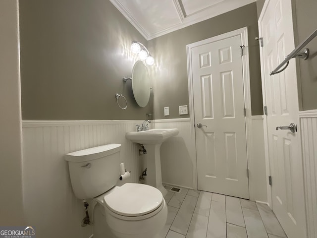 bathroom featuring crown molding, a sink, a wainscoted wall, toilet, and marble finish floor