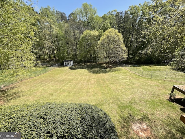 view of yard featuring an outdoor structure, fence, and a storage shed