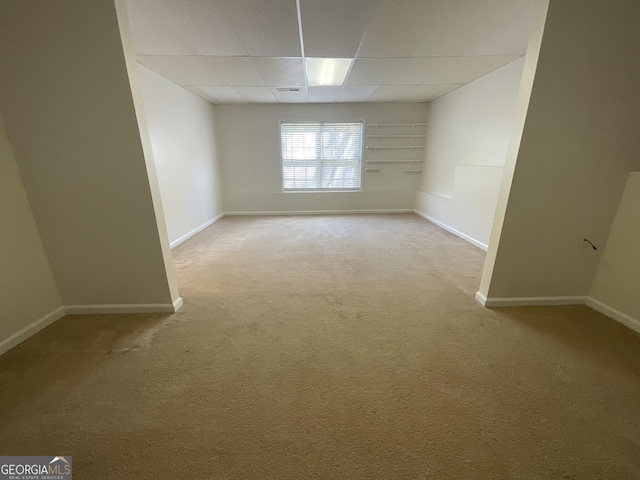 empty room featuring light colored carpet, a paneled ceiling, and baseboards
