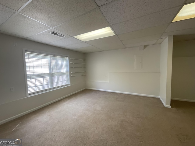 carpeted empty room featuring baseboards, visible vents, and a paneled ceiling