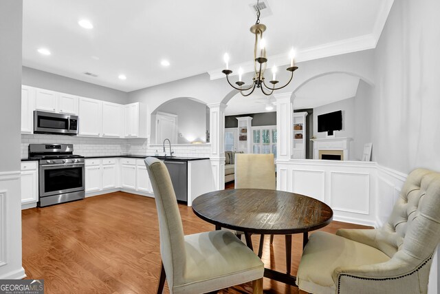 6330 Elmshorn Way, Alpharetta, GA 30004 - dining area featuring light wood-style floors, a decorative wall, arched walkways, ornate columns, and visible vents