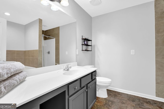 6330 Elmshorn Way, Alpharetta, GA 30004 - bathroom featuring baseboards, toilet, stone finish floor, vanity, and tiled shower