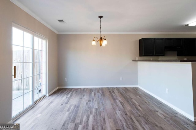 unfurnished dining area with light wood-style floors, crown molding, visible vents, a chandelier, and baseboards